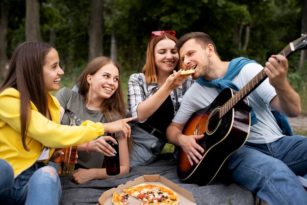 Bezpłatne zdjęcie Średnio strzałowi przyjaciele z muzyką i pizzą