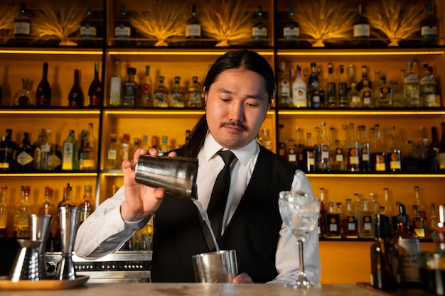 Bezpłatne zdjęcie Średnio strzałowy barman przygotowujący drinka