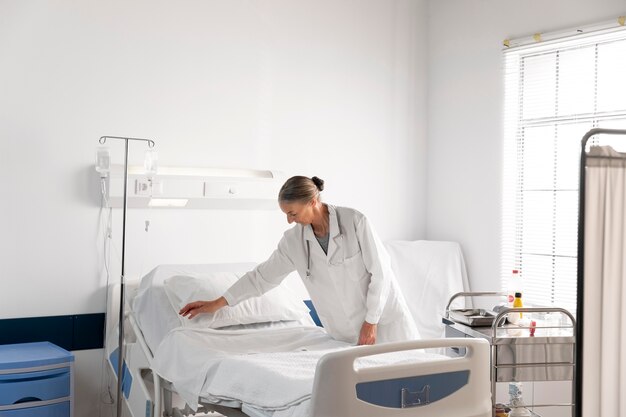 Średnio strzałowy lekarz sprawdzający łóżko pacjenta