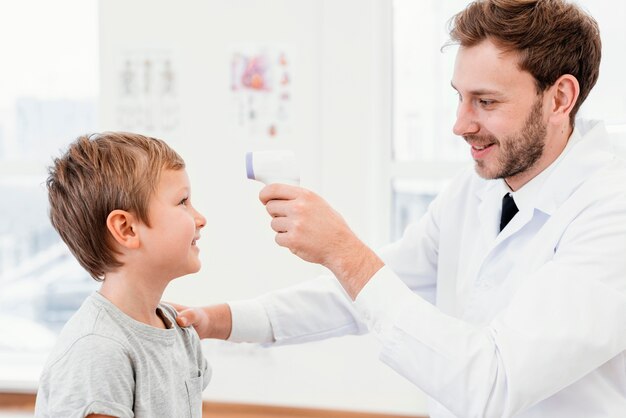 Średnio strzałowy lekarz sprawdzający temperaturę dziecka
