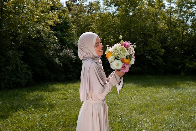 Średnio strzelająca muzułmańska kobieta pozuje z kwiatami