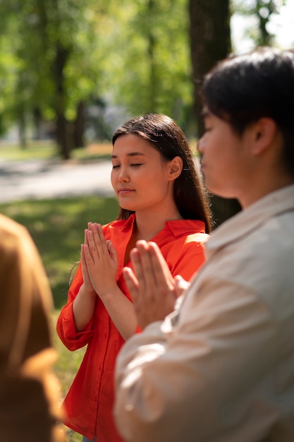 Średnio ujęcia młodzi ludzie modlący się na świeżym powietrzu