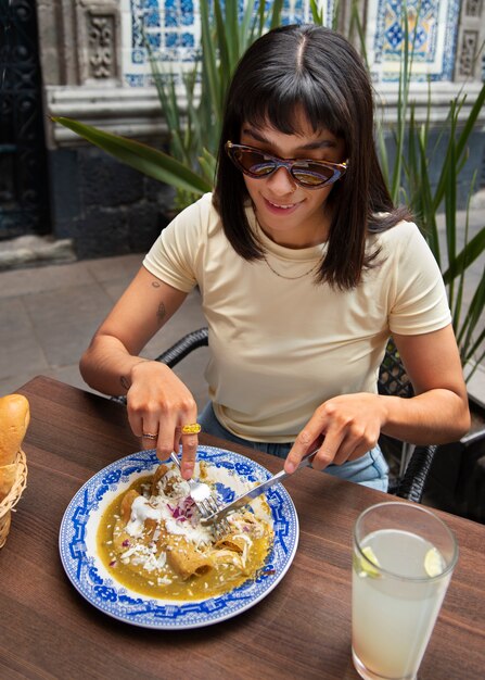 Bezpłatne zdjęcie Średnio ujęcie meksykańskiej kobiety jedzącej jedzenie ranchero