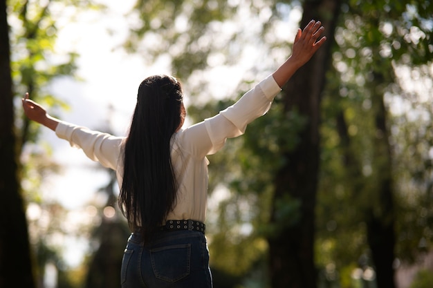 Bezpłatne zdjęcie Średnio ujęcie młodej kobiety modlącej się na świeżym powietrzu