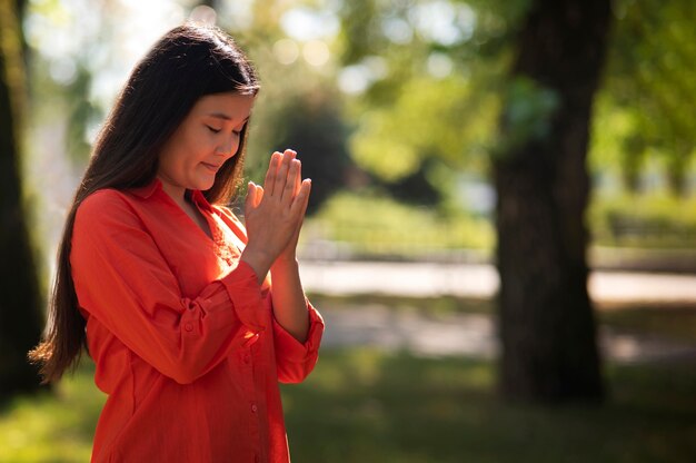 Średnio ujęcie młodej kobiety modlącej się na świeżym powietrzu