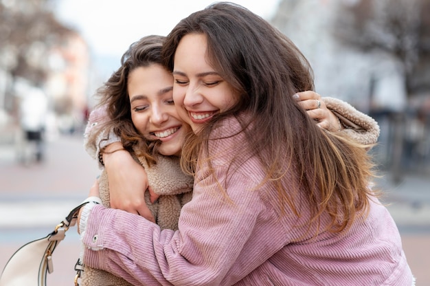 Średnio ujęcie przytulających się uśmiechniętych przyjaciół