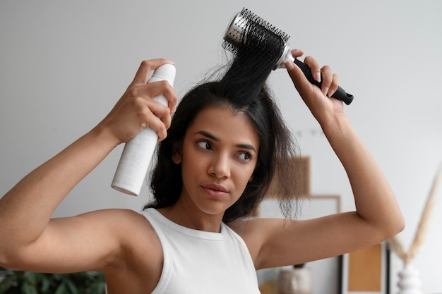 Średnio ustrzelona kobieta używająca suchego szamponu w domu