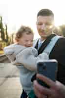 Bezpłatne zdjęcie Średnio ustrzelony ojciec trzymający dziecko w nosidełku