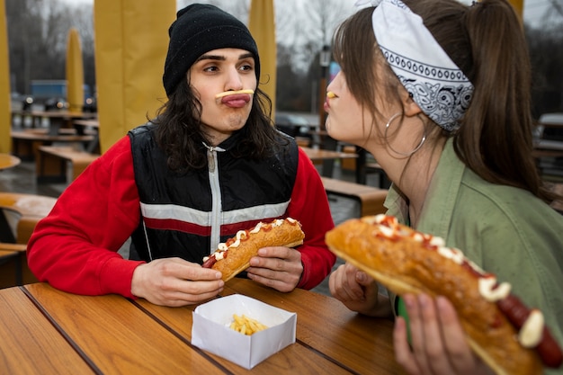 Bezpłatne zdjęcie Średnio zastrzeleni przyjaciele jedzący fast foody w zabawny sposób