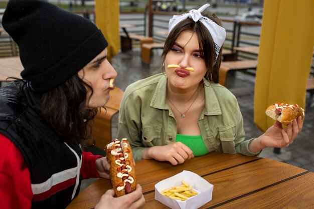 Średnio zastrzeleni przyjaciele jedzący fast foody w zabawny sposób