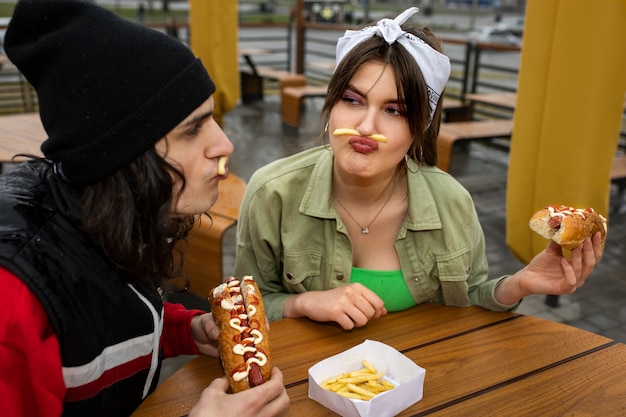 Średnio zastrzeleni przyjaciele jedzący fast foody w zabawny sposób