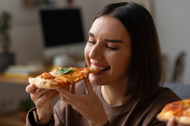Średnio zastrzelona kobieta jedząca pyszną pizzę
