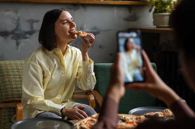 Średnio zastrzelona kobieta jedząca pyszną pizzę