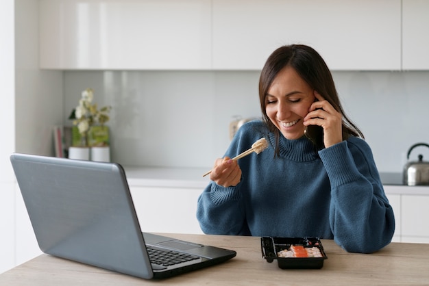 Bezpłatne zdjęcie Średnio zastrzelona kobieta jedząca sushi w domu