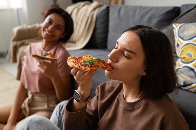 Średnio zastrzelone kobiety jedzące pyszną pizzę