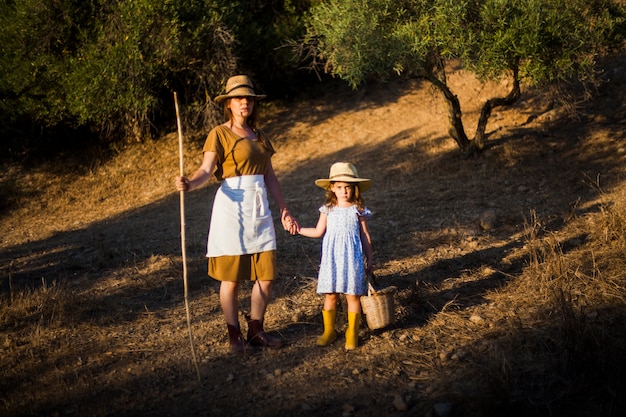 Średniorolna kobieta trzyma jej córki ręki pozycję w polu