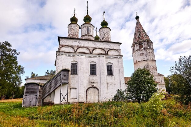 Stara cerkiew na wsi. Letni widok z kwiecistą łąką. Słoneczny dzień, błękitne niebo z chmurami.