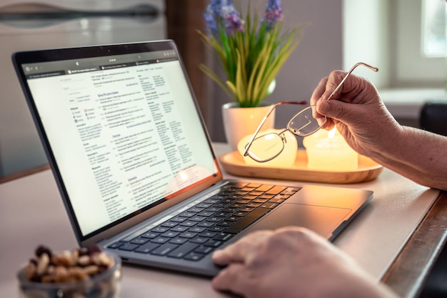 Stara kobieta czyta wiadomość na ręce zbliżenia laptopa