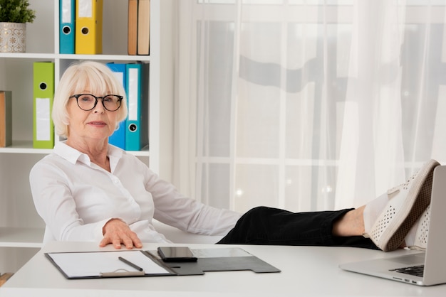 Stara kobieta siedzi w jej biurze z eyeglasses
