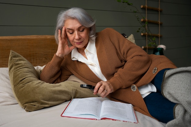 Bezpłatne zdjęcie starsza kobieta czyta przy użyciu szkła powiększającego