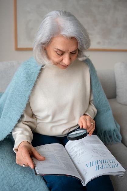 Starsza kobieta czytająca przy użyciu szkła powiększającego