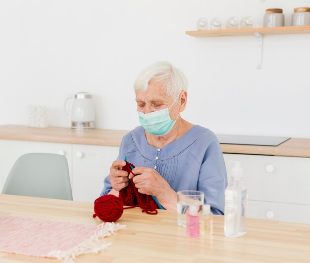 Starsza kobieta dziani w domu z medyczną maską