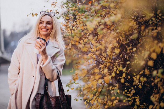 Starsza kobieta pije kawę na zewnątrz jesień parka