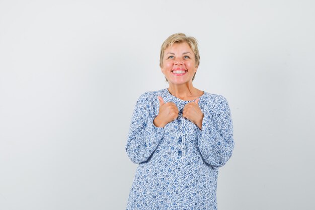 Starsza kobieta pokazuje podwójne kciuki w koszuli i szuka zadowolony.