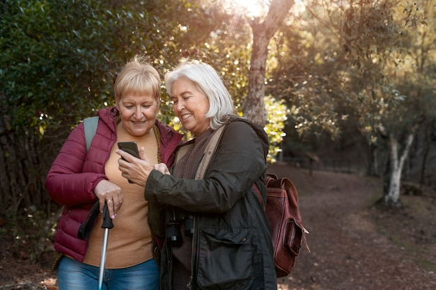 Bezpłatne zdjęcie starsza kobieta pokazuje swojemu przyjacielowi coś na swoim smartfonie podczas podróży