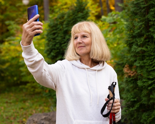 Bezpłatne zdjęcie starsza kobieta robi selfie podczas trekkingu na świeżym powietrzu