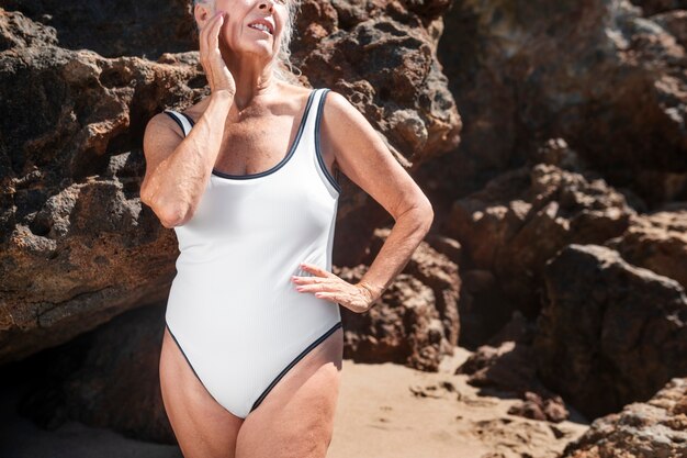 Starsza kobieta w letniej sesji w białym jednoczęściowym stroju kąpielowym
