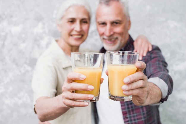 Starsza para trzyma sok pomarańczowego