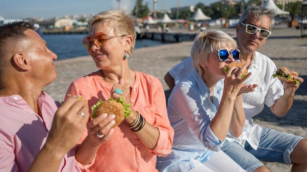 Starsze pary razem na plaży delektując się hamburgerami