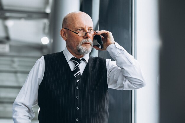 Starszy biznesmen opowiada na telefonie przy biurem
