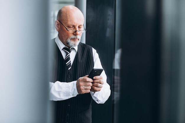 Starszy biznesmen opowiada na telefonie przy biurem