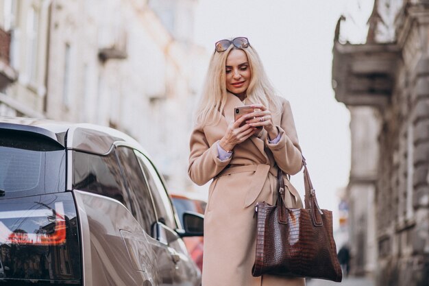 Starszy bizneswoman opowiada na telefonie jej elektrycznym samochodem