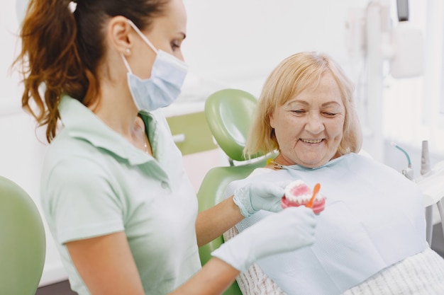 Bezpłatne zdjęcie starszy kobieta po leczeniu stomatologicznym w gabinecie dentystycznym. kobieta jest leczona na zęby