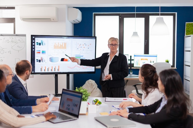 Bezpłatne zdjęcie starszy lider firmy przeprowadza burzę mózgów w sali konferencyjnej personel firmy omawia nową aplikację biznesową z kolegami patrzącymi na ekran