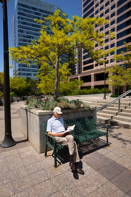 Starszy mężczyzna czyta książkę na ławce na zewnątrz