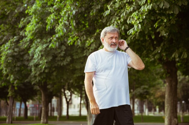 Starszy mężczyzna jako biegacz z trackerem fitness na ulicy miasta.