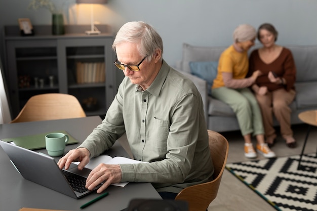 Starszy mężczyzna korzysta z laptopa siedzącego przy biurku w salonie