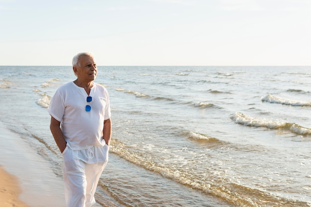 Starszy mężczyzna podziwiając widok podczas spaceru po plaży