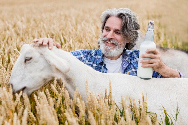 Starszy mężczyzna trzyma butelkę koziego mleka