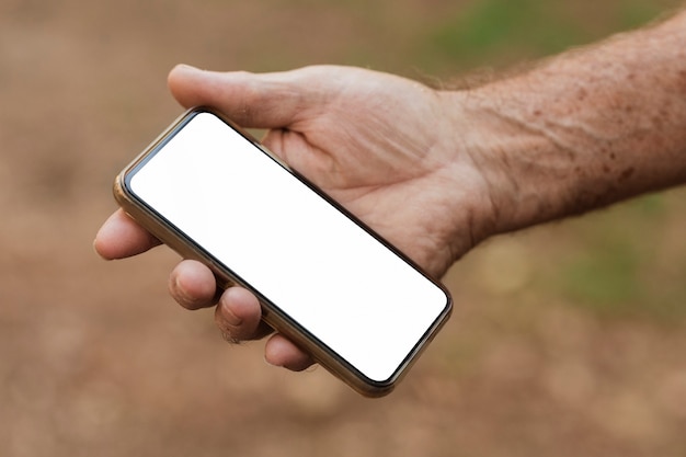 Starszy mężczyzna trzyma smartfon z białym ekranem