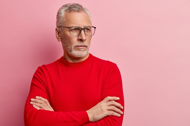 Starszy mężczyzna ubrany w czerwony sweter i modne okulary