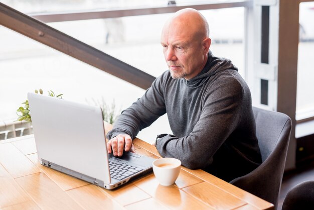 Starszy mężczyzna używa laptop