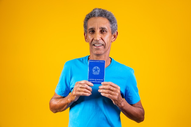 Starszy pracownik posiadający w ręku brazylijską kartę pracy. osoba w podeszłym wieku posiadająca brazylijską kartę pracy