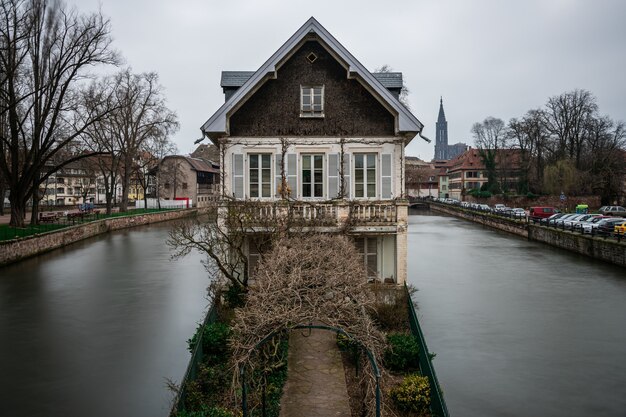 Stary budynek otoczony wodą i zielenią pod zachmurzonym niebem w Strasburgu we Francji