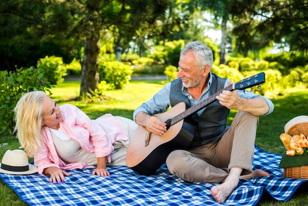 Stary człowiek gra na gitarze dla swojej kobiety