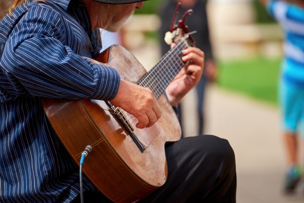 Stary człowiek gra na gitarze na ulicy